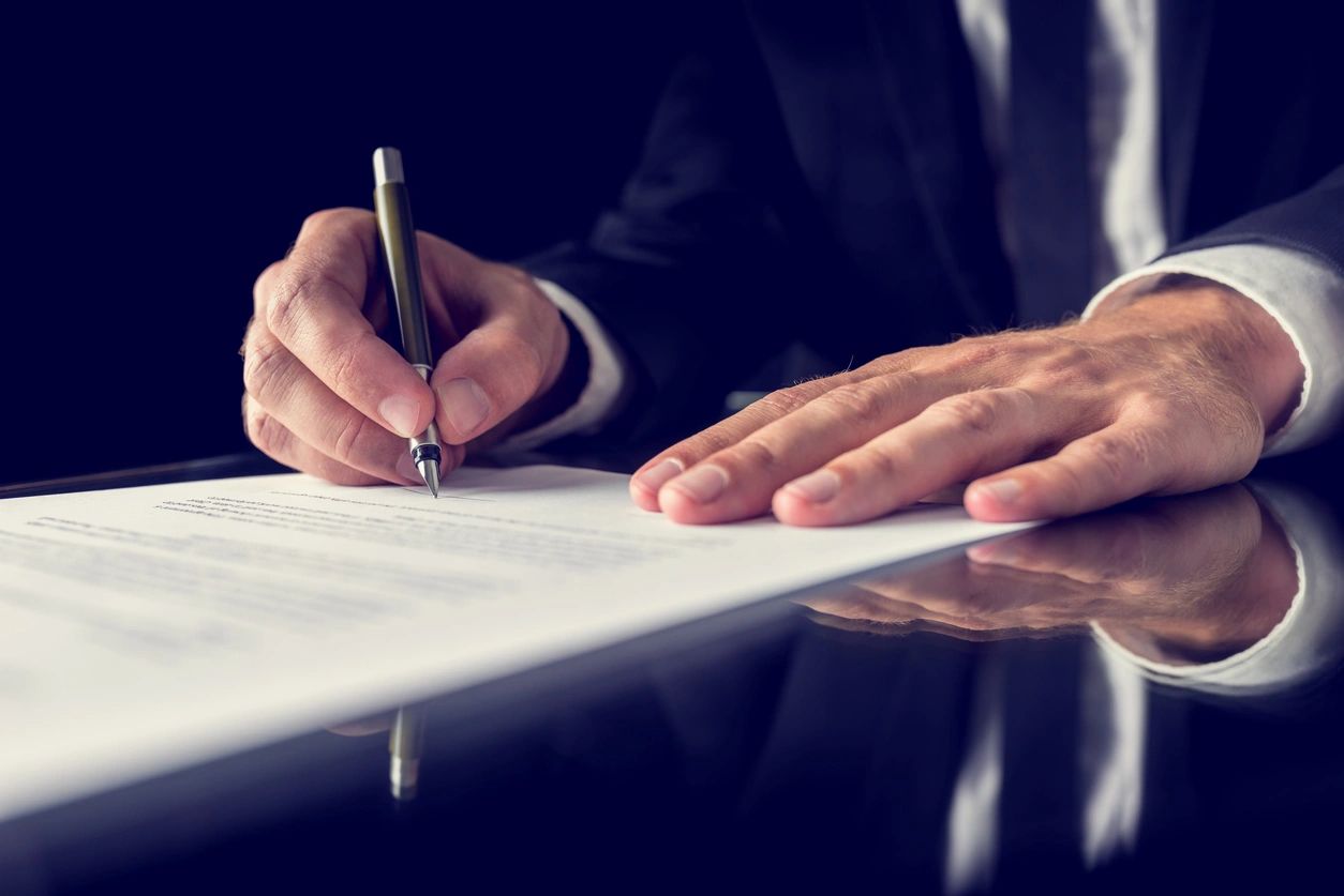 Person signing a document with a pen.